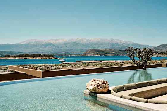 Et infinitybasseng med utsikt over havet og en fjellkjede i bakgrunnen. (AI-generert tekst)