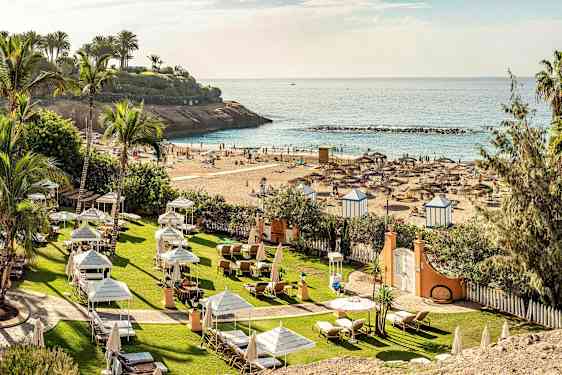 Utsikt over strand med parasoller og solsenger ved sjøen. (AI-generert tekst)