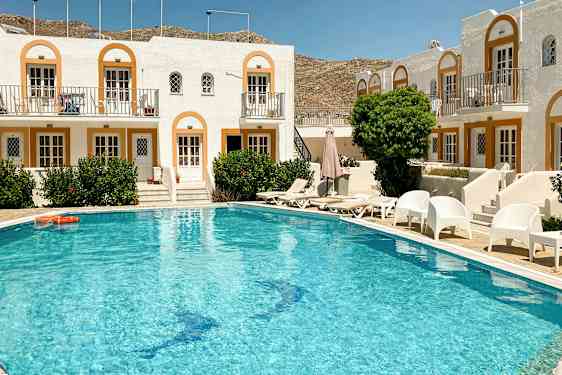 Et basseng foran en rekke med hvite bygninger i middelhavsstil. (AI-generert tekst)