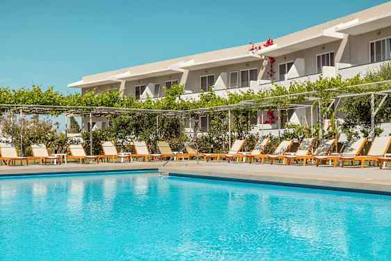 Utendørs basseng foran en rekke solsenger og et hotell i bakgrunnen. (AI-generert tekst)