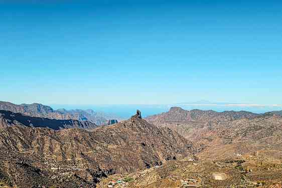 Landskap med fjell og en distinkt klippeformasjon under blå himmel. (AI-generert tekst)