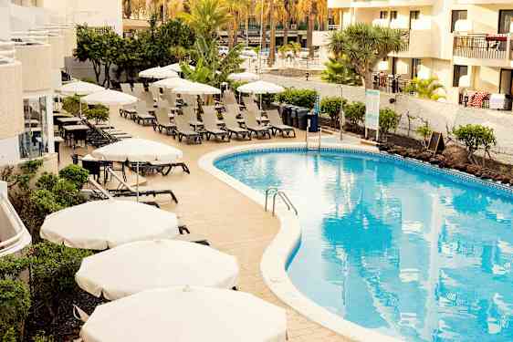 Bassengområde med solsenger og parasoller ved et hotell. (AI-generert tekst)