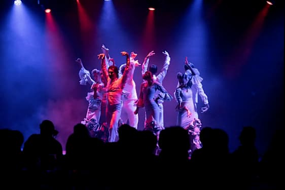 Dansere fremfører en koreografi på en scene med fargebelyst oppsett. (AI-generert tekst)