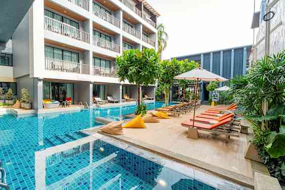 En moderne hotellbygning ved siden av et basseng med solsenger og parasoller. (AI-generert tekst)