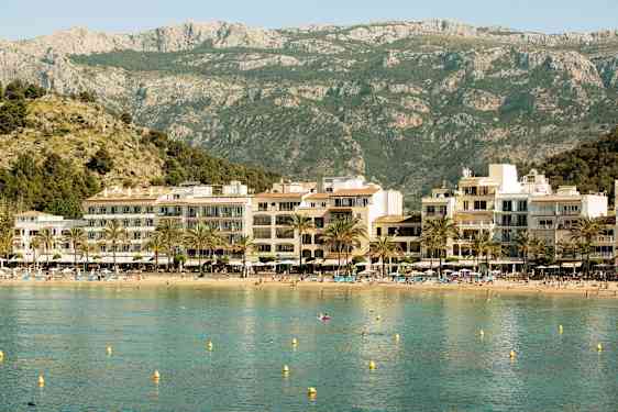 Strand med hotell og fjell i bakgrunnen. (AI-generert tekst)