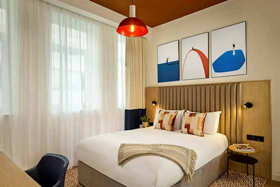 Et stilfullt hotellrom med en stor seng og moderne kunstverk på veggen. (AI-generert tekst)