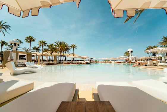 Et luksuriøst basseng omgitt av solsenger og parasoller i et sommerlig miljø. (AI-generert tekst)