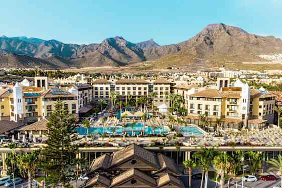 Hotellbygninger med bassengområde og fjell i bakgrunnen. (AI-generert tekst)