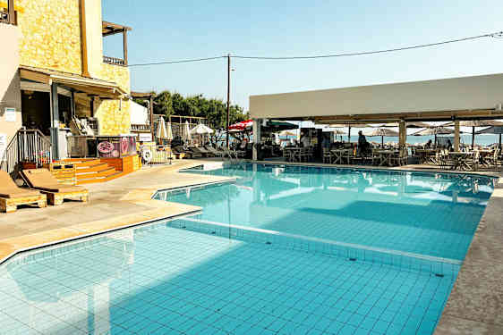 Et svømmebasseng med solsenger og en nærliggende kafé. (AI-generert tekst)