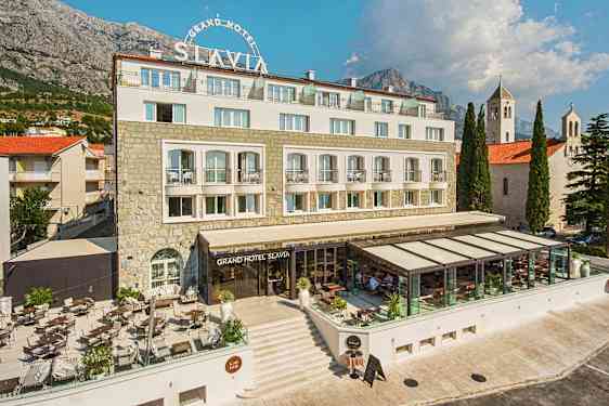 Bilde av Grand Hotel Slavia med utendørsterrasse og glasset restaurantområde. (AI-generert tekst)