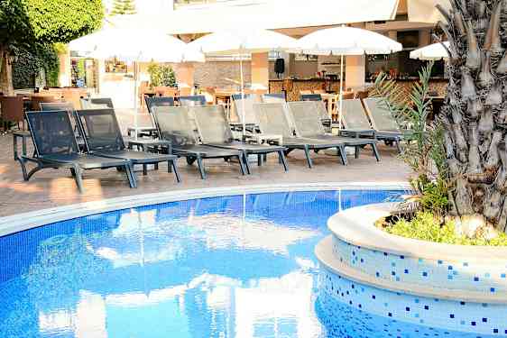 Solstoler ved et bassengkanten med parasoller i bakgrunnen. (AI-generert tekst)