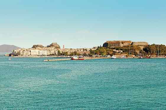 En by ved havet med historiske bygninger og en festning på en høyde. (AI-generert tekst)