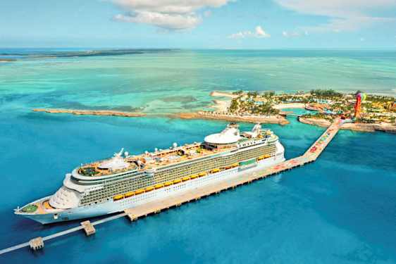 Et cruiseskip ligger ved en kai i et tropisk miljø med turkist vann og øyer i bakgrunnen. (AI-generert tekst)