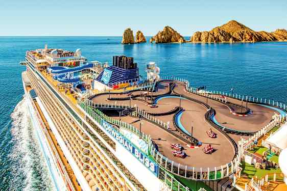 Et cruiseskip med en gokartbane på dekk, omgitt av havet og klippelandskap i bakgrunnen. (AI-generert tekst)