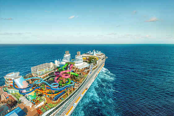 Et stort cruiseskip med vannsklier og bassenger på dekk, omgitt av hav (AI-generert tekst)