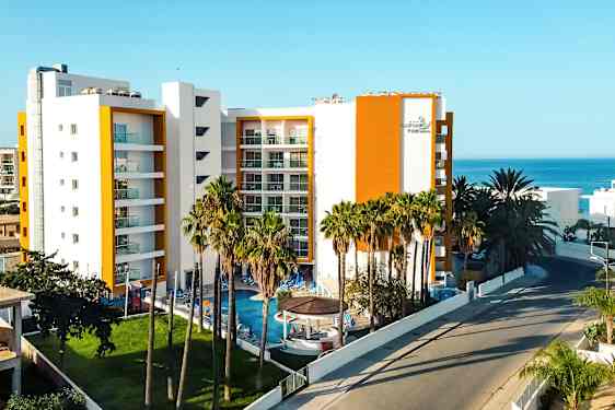 Et hotell med moderne arkitektur og et basseng omgitt av palmer. (AI-generert tekst)