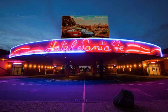 Neonskiltet over inngangen til Hotel Santa Fe med Disney/Pixar-biler på plakaten over. (AI-generert tekst)