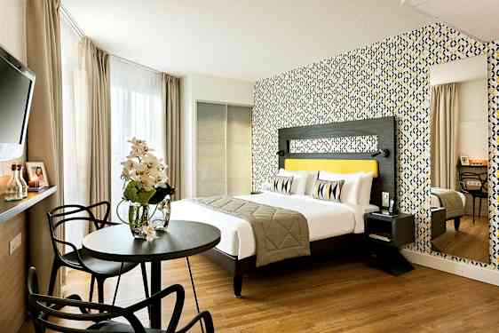 Et moderne hotellrom med en dobbeltseng, fargerikt tapet og sittegruppe. (AI-generert tekst)