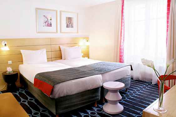 Et hotellrom med to enkeltsenger, et dekorativt sengegavl og et vindu med lysinnslipp. (AI-generert tekst)