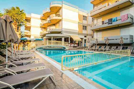 Et utendørs svømmebasseng med solsenger og parasoller ved en moderne bygning. (AI-generert tekst)