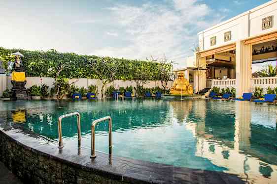 Et innbydende basseng omgitt av solsenger og grøntområder, med en gyllen statue som dekorasjon. (AI-generert tekst)