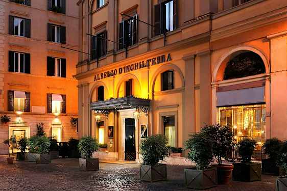 Et hotell med en arkade foran inngangen, opplyst om kvelden. (AI-generert tekst)