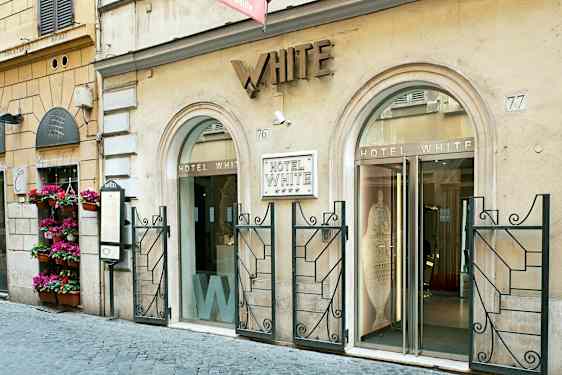 Inngangen til Hotel White, en bygning med to glassdører og dekorert fasade. (AI-generert tekst)