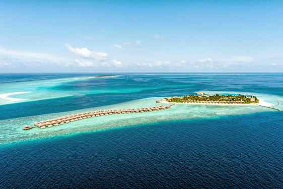 Flyfoto av en tropisk øy og villaer på påler i klart blått hav. (AI-generert tekst)