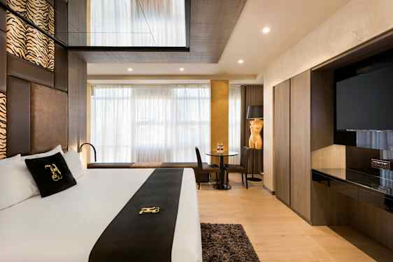 Et moderne hotellrom med dobbeltseng, sittegruppe og TV. (AI-generert tekst)