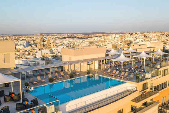 Bilde av en takterrasse med et basseng, solsenger og utsikt over en by i bakgrunnen. (AI-generert tekst)