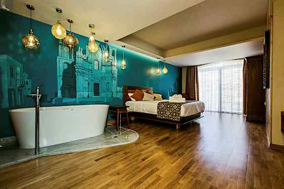 Et hotellrom med en seng, et frittstående badekar og blå veggmalerier. (AI-generert tekst)