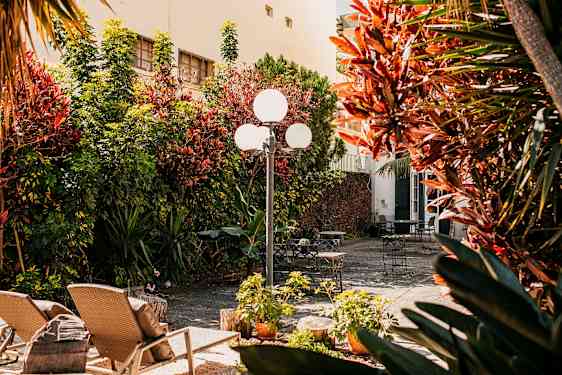 En solfylt gårdsplass med hagemøbler og beplantning. (AI-generert tekst)