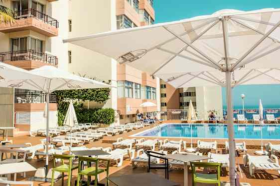 Utendørs bassengområde med solsenger og parasoller ved et hotell. (AI-generert tekst)