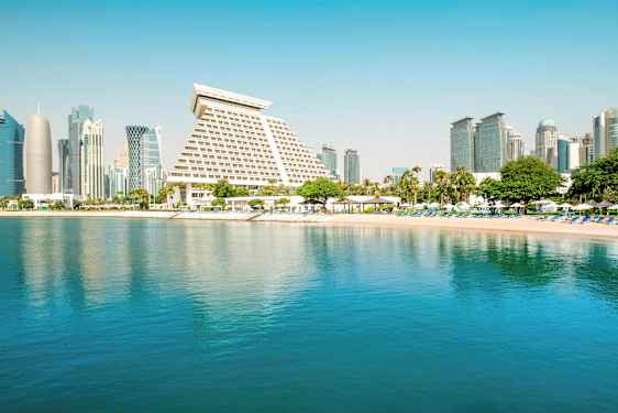 Bilde av en by med moderne arkitektur ved en rolig strand og vann. (AI-generert tekst)