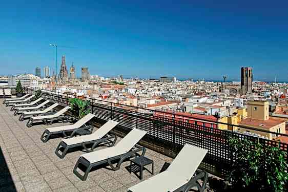 En takterrasse med solsenger og utsikt over en by med kirke og blå himmel. (AI-generert tekst)