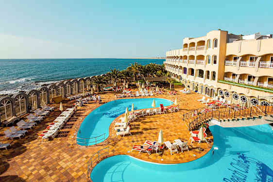 Hotellområde med basseng og havutsikt. (AI-generert tekst)