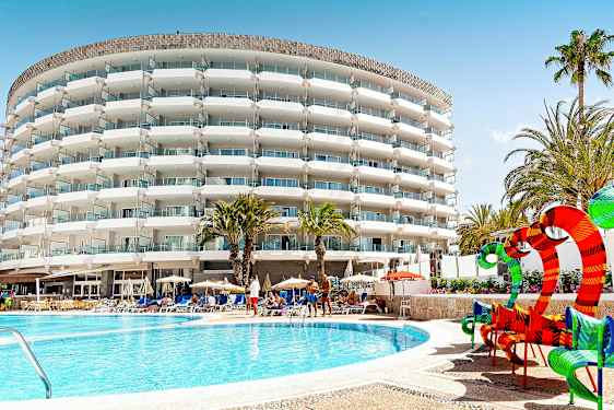 Hotellbygning med balkonger, palmer og bassengområde. (AI-generert tekst)