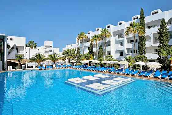 Et hotellbasseng med hvitmalte bygninger og palmer i bakgrunnen. (AI-generert tekst)