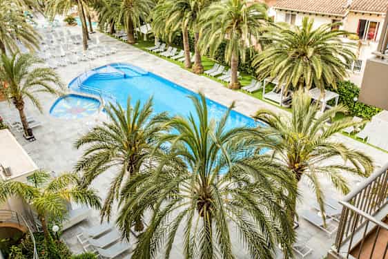 Et svømmebasseng med solsenger og palmer rundt. (AI-generert tekst)