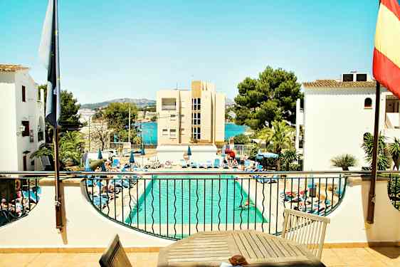 Et basseng med solsenger rundt og bygninger samt trær i bakgrunnen. (AI-generert tekst)