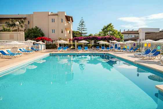 Et utendørsbasseng omgitt av solsenger og parasoller ved et hotell. (AI-generert tekst)