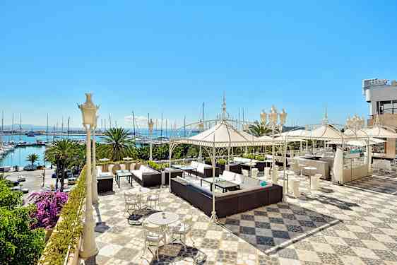 En romslig terrasse med sittegrupper, parasoller og havutsikt. (AI-generert tekst)