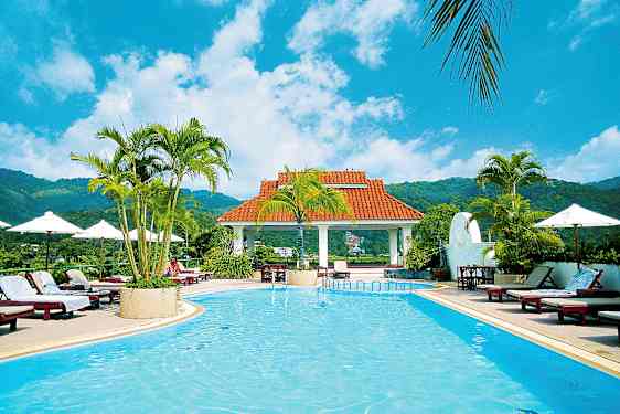 Et utendørsbasseng omgitt av solsenger, parasoller og palmer med et tak i bakgrunnen. (AI-generert tekst)