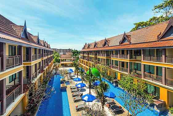 Toetasjes hotellbygg med skråtak omkranser et basseng med solsenger og parasoller. (AI-generert tekst)