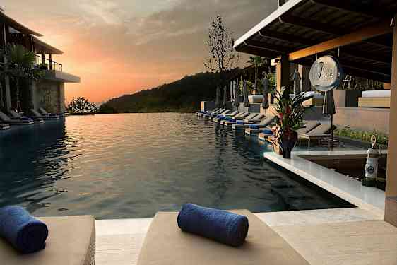 Et uendeligbasseng med solsenger og håndklær på en resort ved solnedgang. (AI-generert tekst)