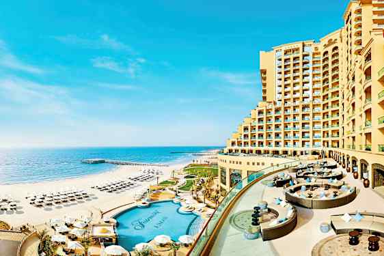 Et hotell beliggende ved strandkanten med basseng og solsenger på stranden. (AI-generert tekst)