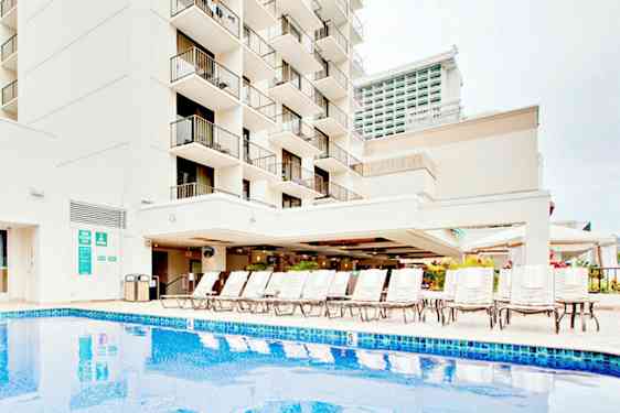 Bilde av en bygning med balkonger, et basseng og solsenger. (AI-generert tekst)