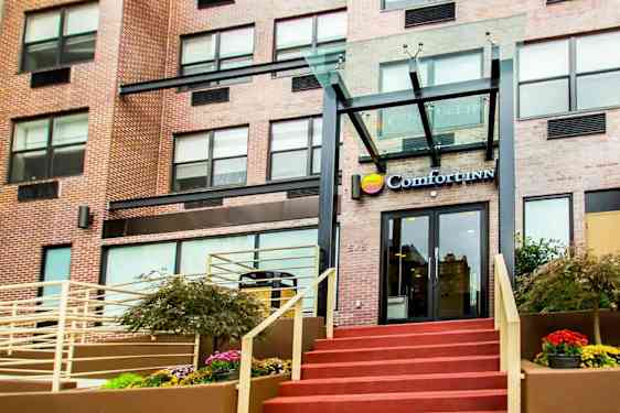 Inngangen til en bygning med teksten "Comfort Inn" over døren. (AI-generert tekst)