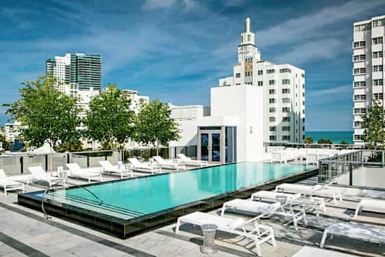 Et takbasseng med solsenger rundt, omgitt av moderne bygninger og grøntområder. (AI-generert tekst)