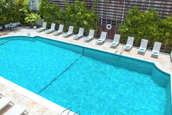 Et basseng omgitt av solsenger og grøntområder. (AI-generert tekst)